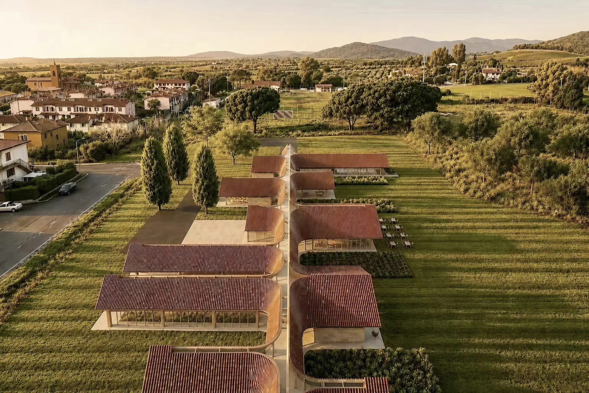 Aerial view of a community with a central walkway, curved terracotta roofs and green gardens.